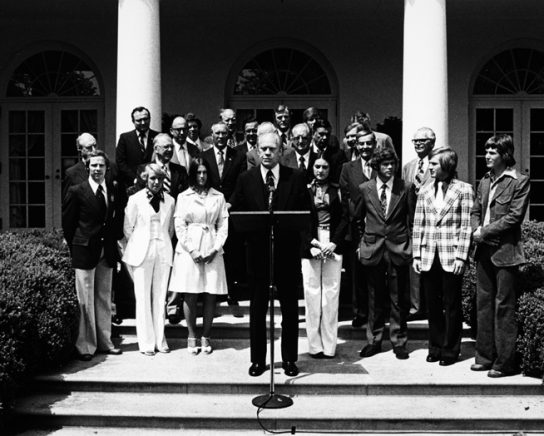 Olympic medalists with President Ford & Senators (1976). Winter Olympic medalists – (left to right) Millins, O’Connor, Mueller, Poulos, Young, Koch in the first row behind President Ford (White House photo).
